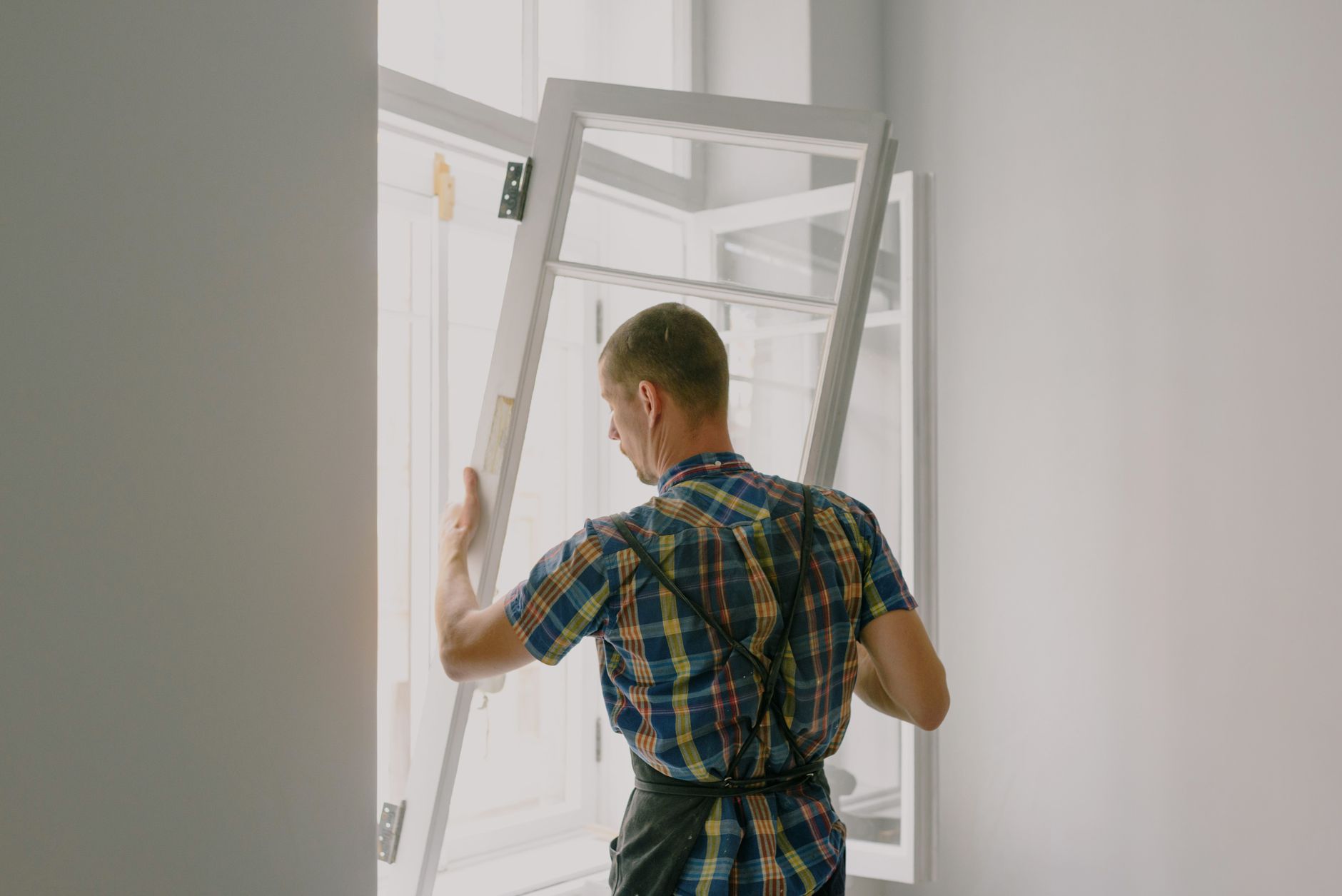 Vakman plaatst een houten raam met glas in een lichte ruimte