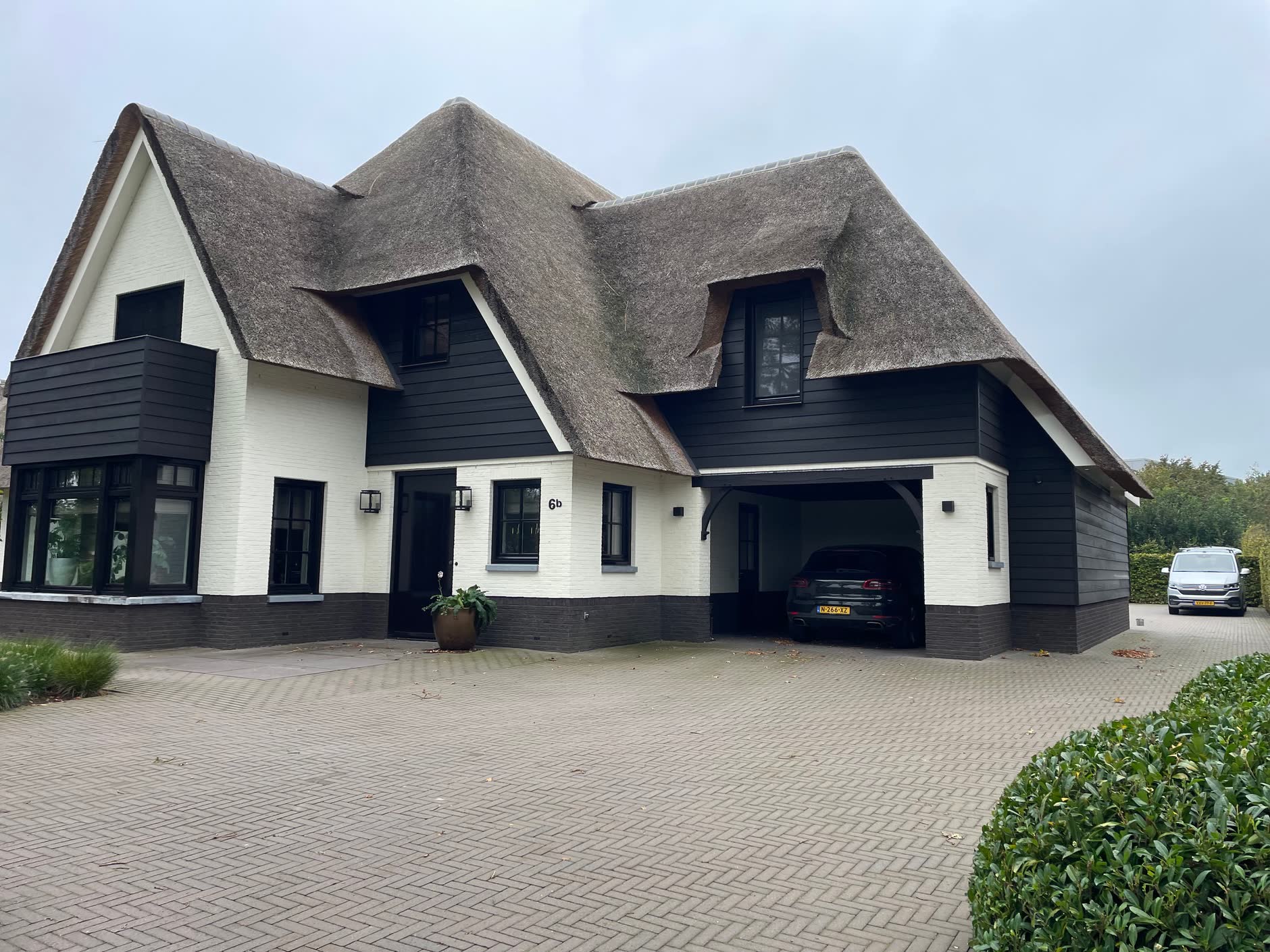 Woning met rieten kap, witte gevel en zwart geschilderde houten delen