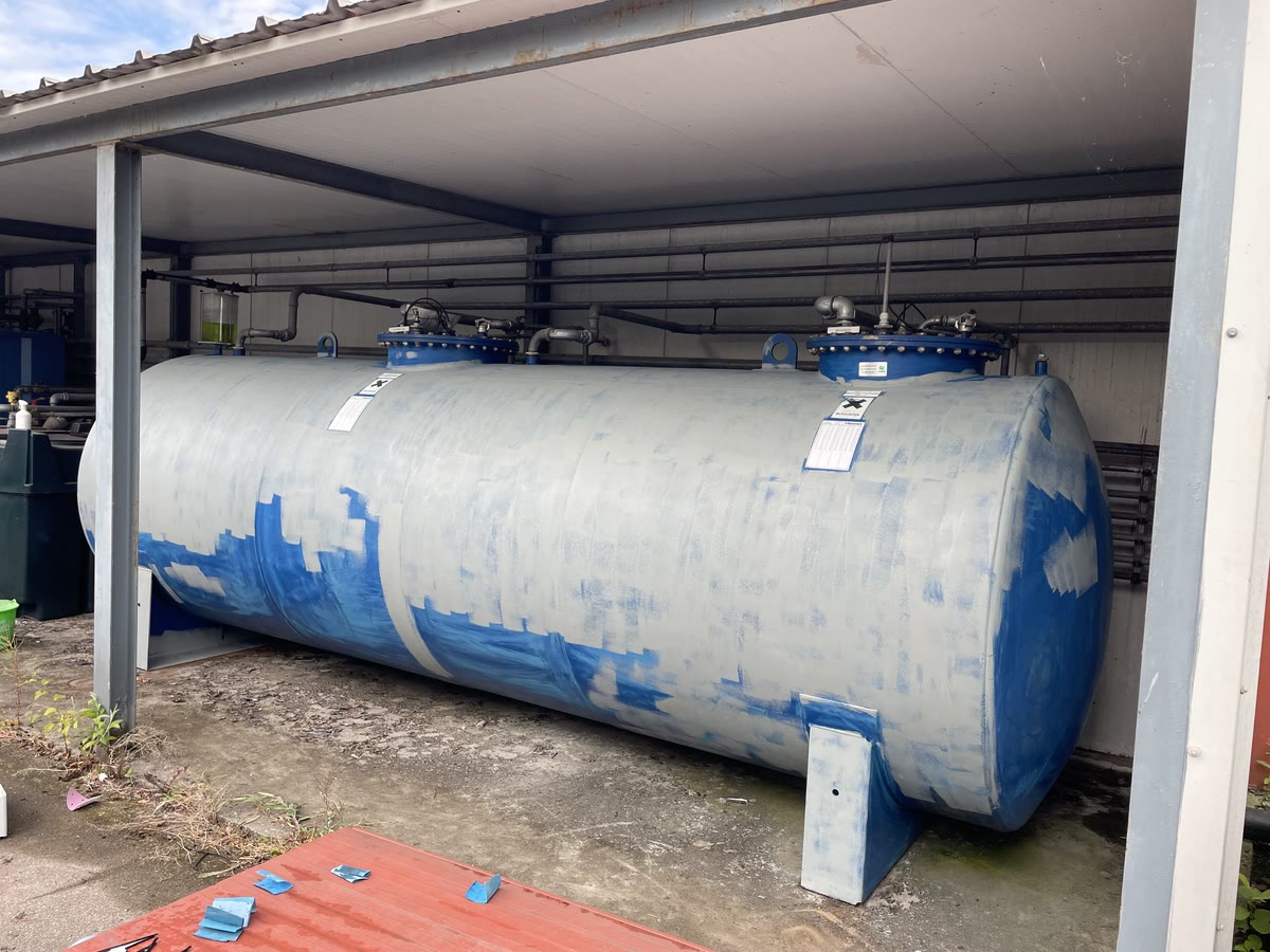 Opslagtank vóór het schilderwerk, met kale en beschadigde plekken in de oude laag